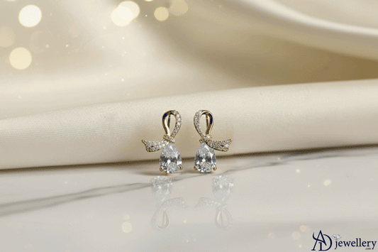 woman wearing dainty pavé bow earrings featuring delicate pear-cut drops, styled with a matching pavé necklace, showcasing an elegant and sparkling jewelry set.