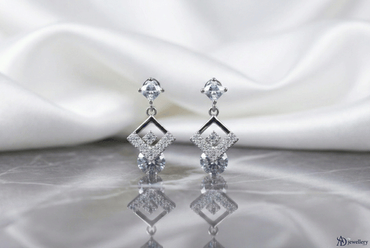 Silver Diamond Kite Dangle Earrings featuring geometric diamond-studded kite shapes displayed on a reflective surface